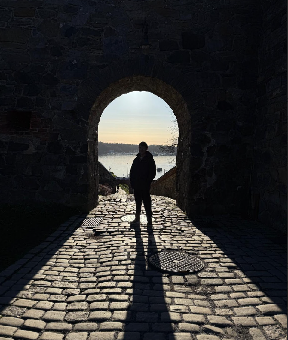 Silhouette of myself standing in front of an archway with the sun shining through it